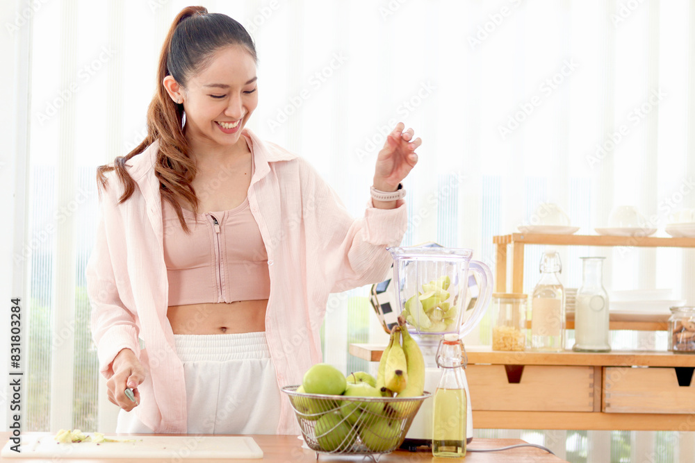 Sporty girl putting mix fruit and vegetable ingredients in blender for making healthy smoothie beverage drink at kitchen. Beautiful happy smiling Asian woman with fruit basket and blender at kitchen. Sporty girl putting mix fruit and vegetable ingredients in blender for making healthy smoothie beverage drink at kitchen. Beautiful happy smiling Asian woman with fruit basket and blender at kitchen.