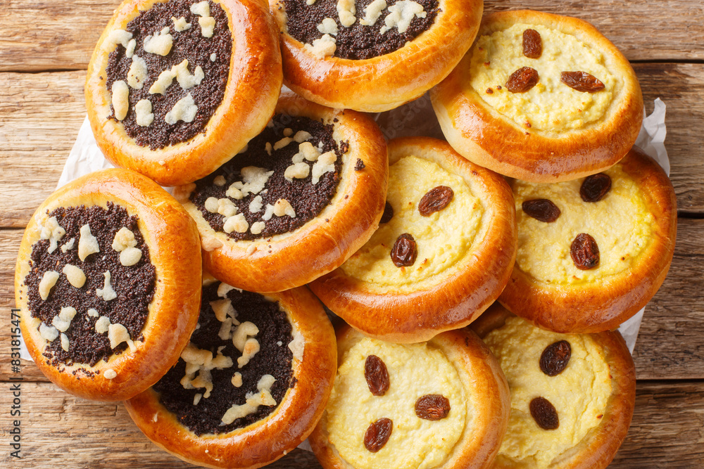 Homemade Czech kolach with traditional filling of cottage cheese with raisins and poppy seeds with streusel close-up on parchment on the table. Horizontal top view from above
