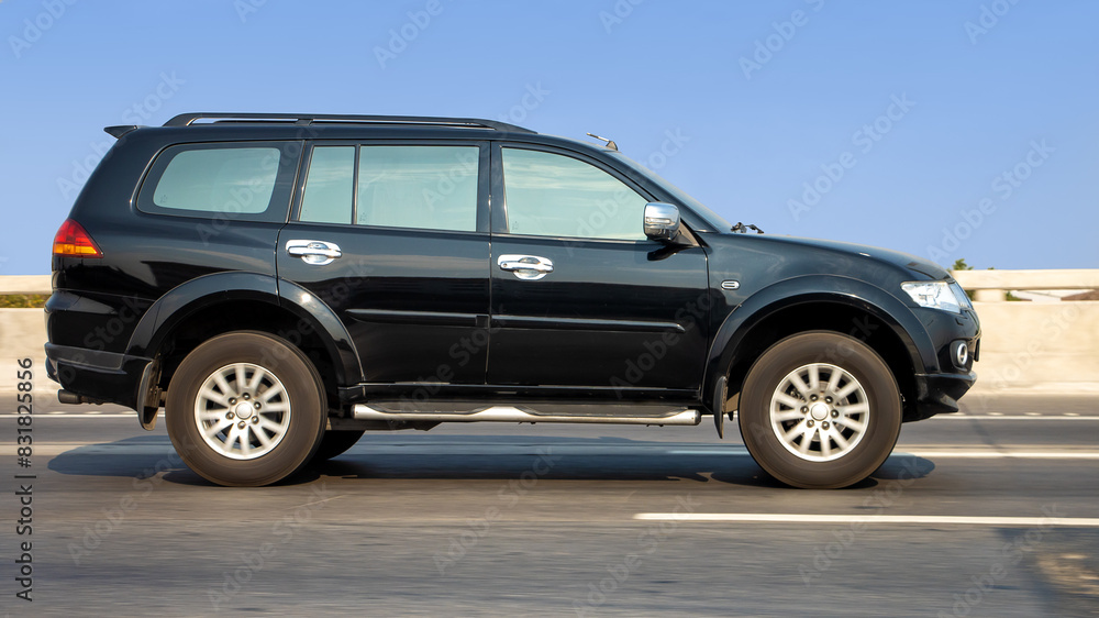 The car goes on the highway on a background of blue sky. An SUV is driving on a motion blurred road. The car goes on the highway on a background of blue sky. An SUV is driving on a motion blurred road.