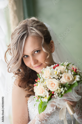 Morning of bride in white dress and elegant hairstyle. A young attractive, happy girl posing with luxurious bouquet. Happiness, purpose and dream wedding. Vertical image.