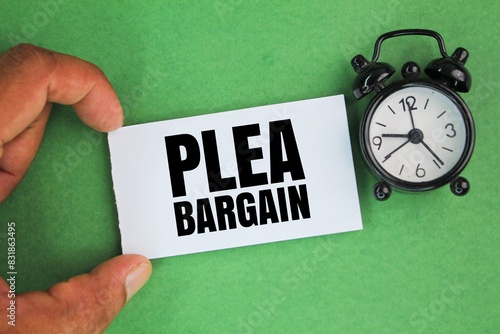 an alarm clock and a hand holding a white paper with the words plea bargain. the concept of court appeal