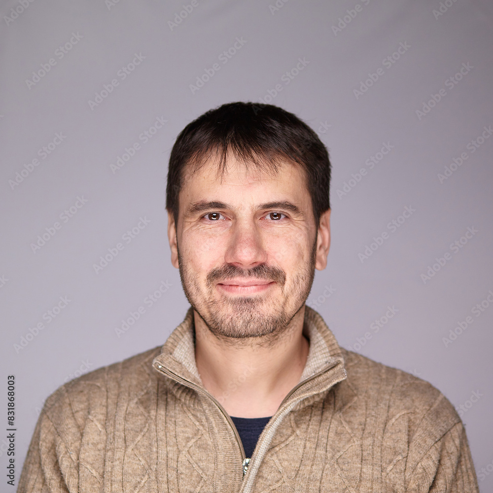 Fototapeta premium A man smiles warmly and confidently at the camera in a studio setting, radiating happiness and self-confidence.