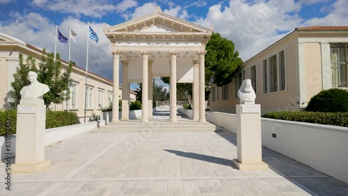 A neoclassical building in Pafos, Cyprus, with columns and busts, under a bright blue sky. photo