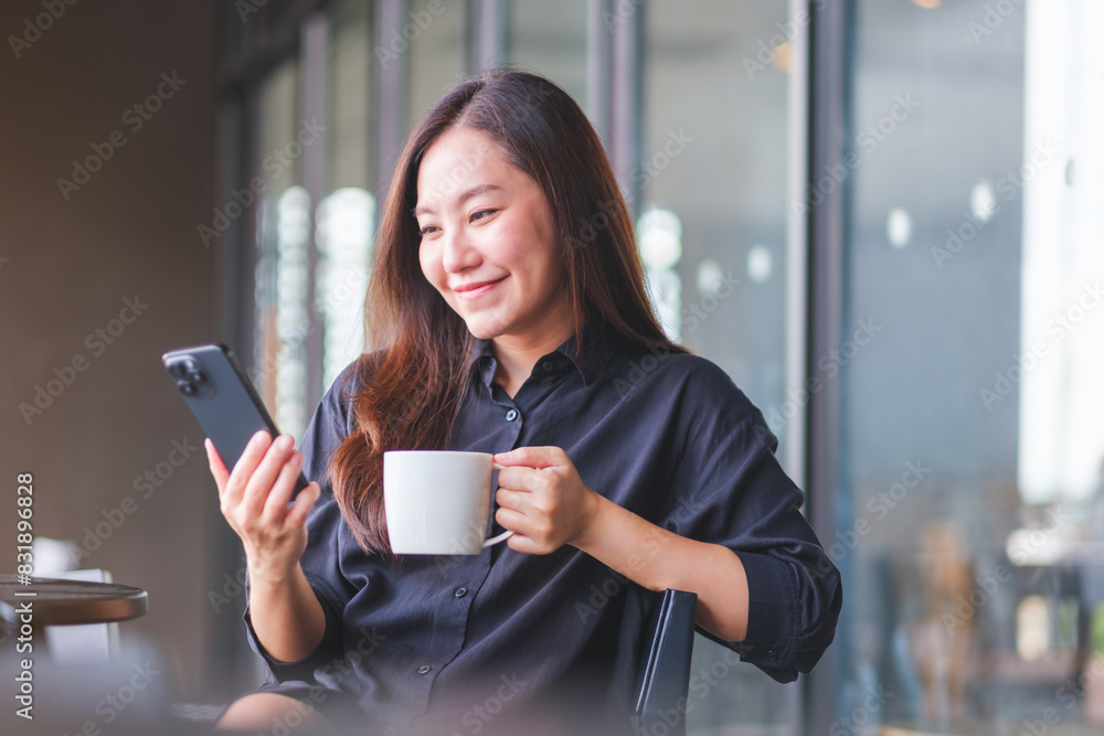 Portrait image of a young woman holding and using mobile phone while drinking coffee in cafe Portrait image of a young woman holding and using mobile phone while drinking coffee in cafe