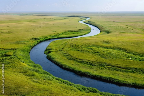 Aerial photograph showcasing a curving river on expansive grasslands with clear skies and minimalistic aesthetics, high-definition quality