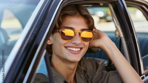 A woman is smiling and wearing sunglasses while sitting in a car. Scene is happy and carefree