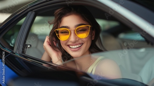 A woman is smiling and wearing sunglasses while sitting in a car. Scene is happy and carefree © Дмитрий Симаков