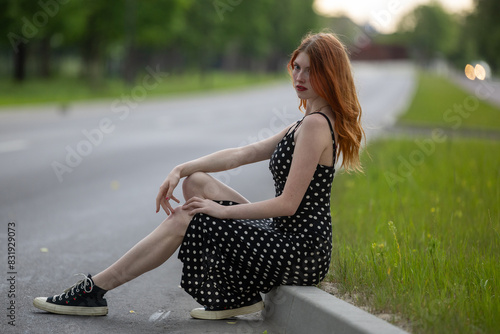 Young beautiful red hair hipster woman sitting on the grass in the city photo