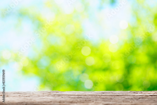 ぼやけた玉ボケの光が重なる緑の背景に木の台