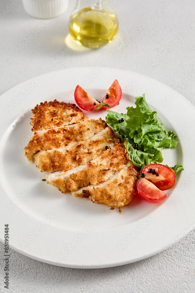Golden crusted chicken fillet with cheese on a bed of lettuce, topped with cherry tomatoes, ideal for recipes and menu designs Golden crusted chicken fillet with cheese on a bed of lettuce, topped with cherry tomatoes, ideal for recipes and menu designs
