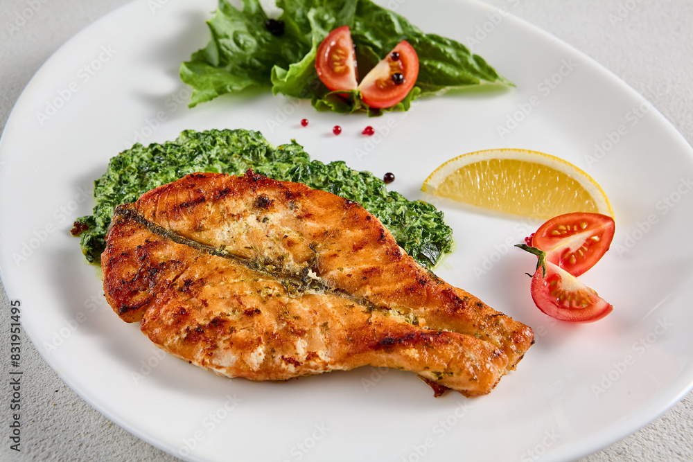 Pan-seared salmon steak with fresh spinach on white plate, perfect for healthy lifestyle and seafood cuisine presentations Pan-seared salmon steak with fresh spinach on white plate, perfect for healthy lifestyle and seafood cuisine presentations