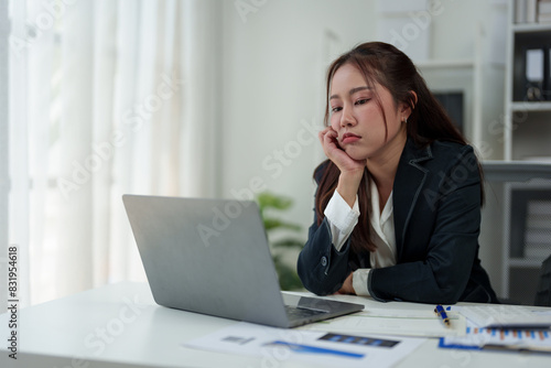A businesswoman who is tired, stressed, and sore from working for a long time. After waiting for news Unsuccessful business approval results on laptop in office. Startup time concept, office syndrome