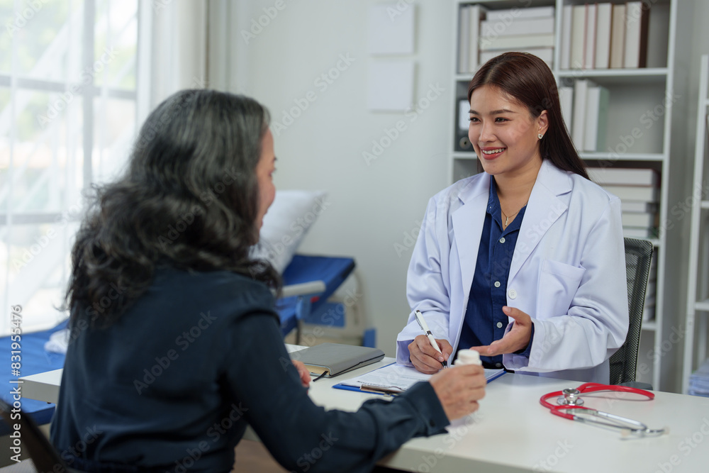 Obraz premium Confident Asian female doctor explains and questions a retired female patient attending a private clinic for treatment and therapy. Health concept, health insurance.