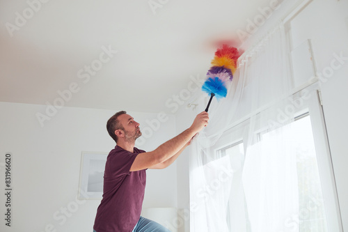 Wall Mural Man cleaning apartment with dusting broom.