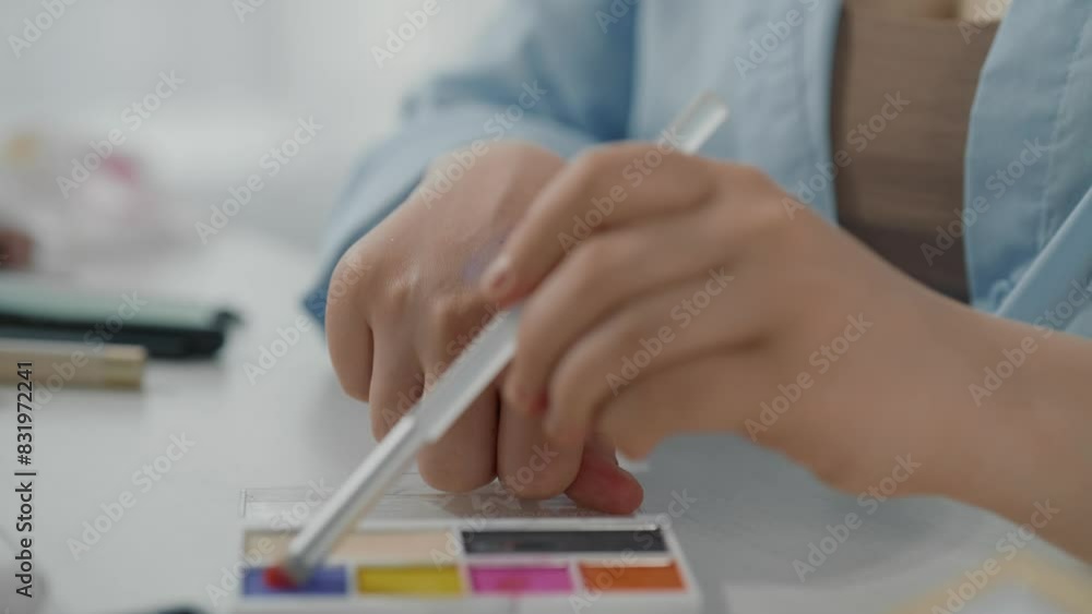 Closeup view of young lady hands and bright eyeshadow palette in beauty studio. Professional makeup artist taking bright color by cosmetic brush and applying on skin of hand, swatch of eyeshadows Closeup view of young lady hands and bright eyeshadow palette in beauty studio. Professional makeup artist taking bright color by cosmetic brush and applying on skin of hand, swatch of eyeshadows