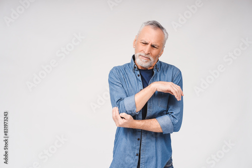 Photography Portrait of gray-haired bearded mature man feeling pain in elbow posing in studi