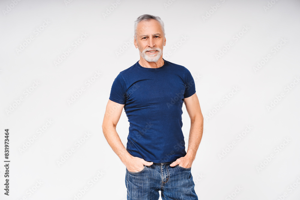 Fototapeta premium Attractive mature grey haired man holding hands in pockets isolated over white background