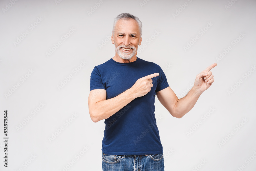 Smiling bearded gray-haired man pointing to his side in studio over white background Smiling bearded gray-haired man pointing to his side in studio over white background