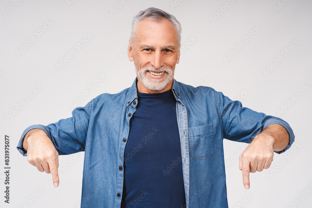 Happy mature gray-haired bearded man pointing down by fingers looking at camera, isolated Happy mature gray-haired bearded man pointing down by fingers looking at camera, isolated