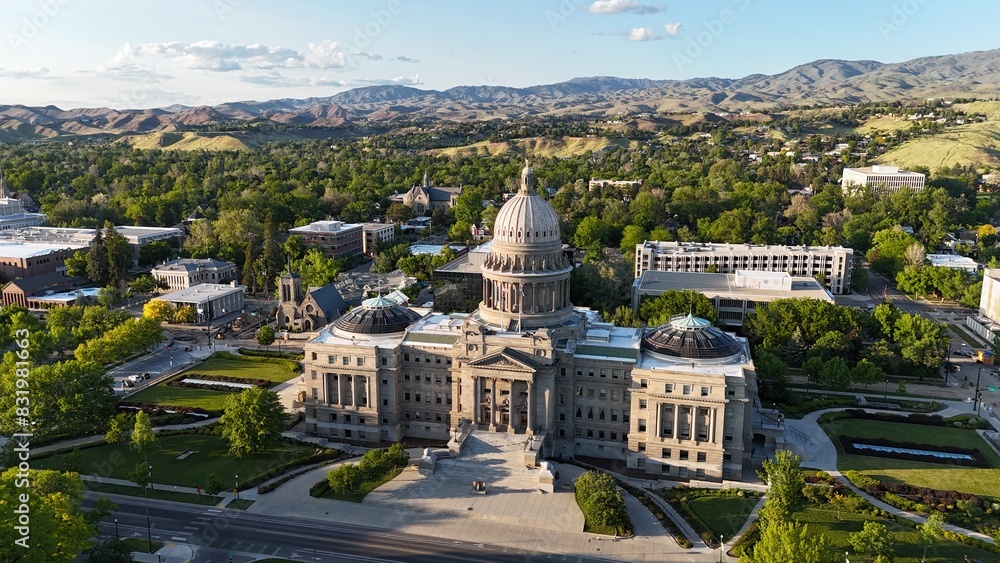 The Boise State Capital building surrounded by greenery and other buildings in early morning The Boise State Capital building surrounded by greenery and other buildings in early morning