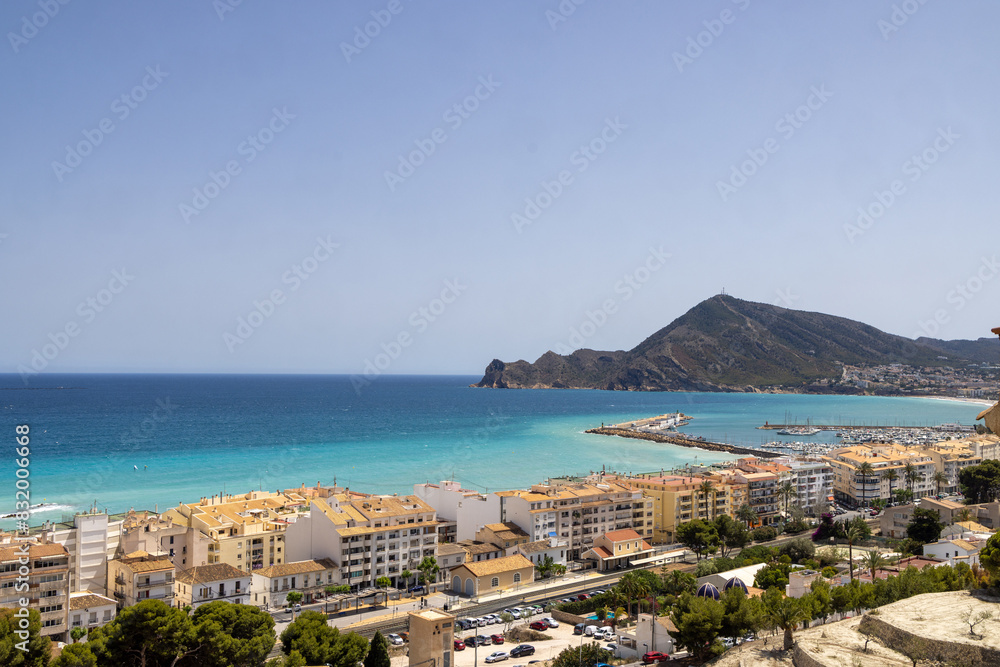 Photo aerial footage of the beautiful city of Altea in Spain showing a view from the city over looking the beach front harbour and mountains by the ocean front in the summer time