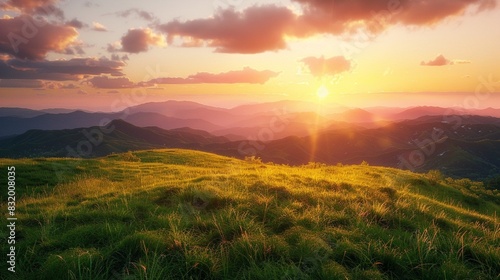 A sunset over a grassy hill with mountains in the background. © Pik_Lover
