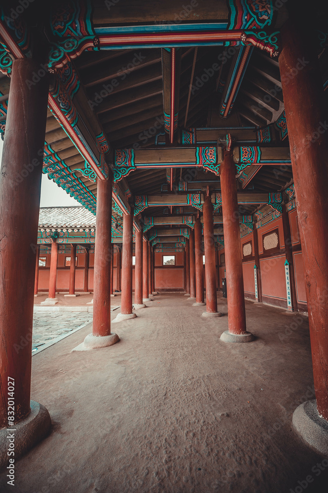 A colonnade at the Geunjeongmun Gate (or third gate) of the Gyeongbokgung Palace complex in Seoul, Korea shows the row of red columns topped by ornately painted wood beams.