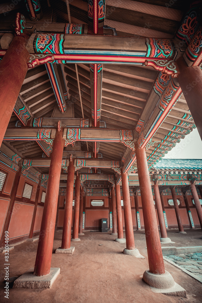 A colonnade at the Geunjeongmun Gate (or third gate) of the Gyeongbokgung Palace complex in Seoul, Korea shows the row of red columns topped by ornately painted wood beams.