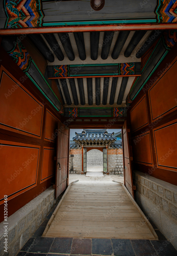 A colonnade at the Geunjeongmun Gate (or third gate) of the Gyeongbokgung Palace complex in Seoul, Korea shows the row of red columns topped by ornately painted wood beams.