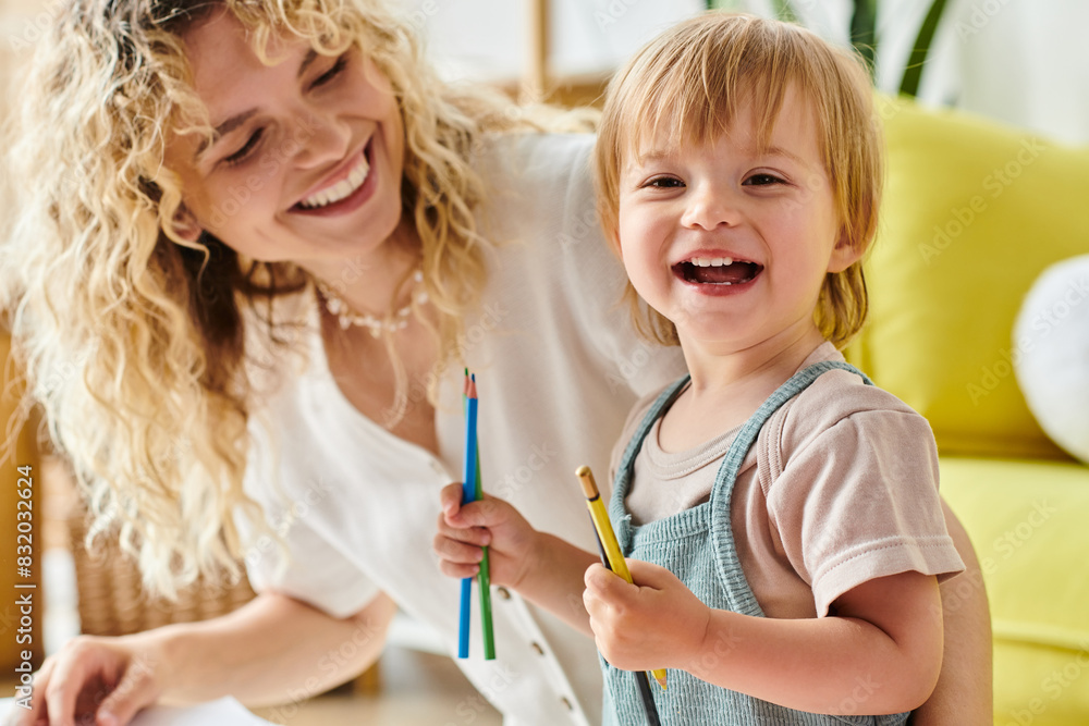 A curly-haired mother and her toddler daughter hold pencils in their hands, engaging in the Montessori method of education at home. A curly-haired mother and her toddler daughter hold pencils in their hands, engaging in the Montessori method of education at home.