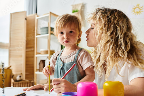 A curly mother and her toddler daughter engage in the Montessori method of education at a table. © LIGHTFIELD STUDIOS