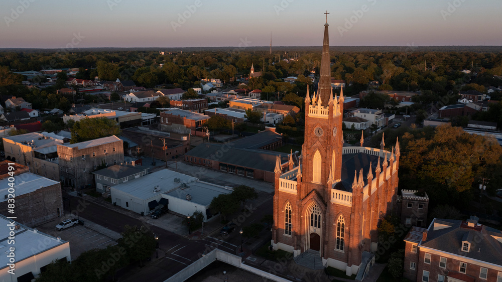 Fototapeta premium Natchez, Mississippi, USA - April 21, 2024: Sunset light shines on a historic church and landscape of downtown Natchez.