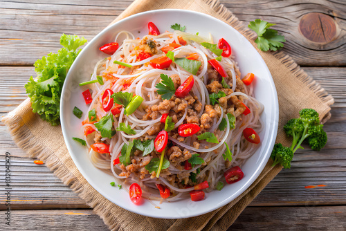 (Yum woon sen) is a type of Thai salad made with clear bean vermicelli and meat in white plate. top view