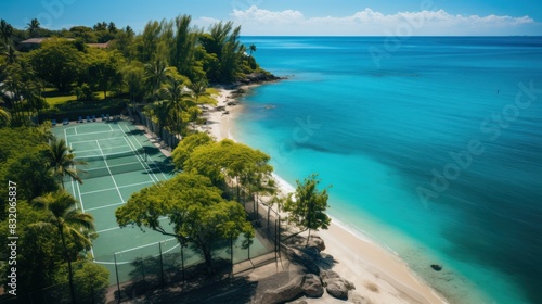 Overhead view of a lush tropical beach resort featuring a tennis court beside the clear blue sea photo