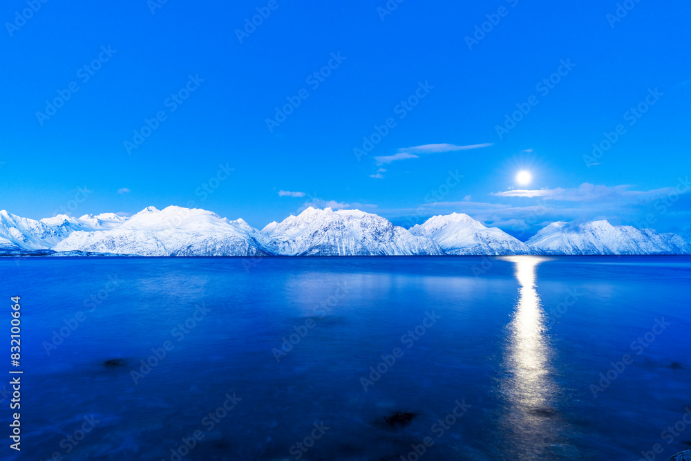 Full moon above snowy peaks in the Arctic landscape reflecting in the cold water of the fjord at dusk, Lyngen fjord, Lyngen Alps, Troms og Finnmark, Norway, Scandinavia Full moon above snowy peaks in the Arctic landscape reflecting in the cold water of the fjord at dusk, Lyngen fjord, Lyngen Alps, Troms og Finnmark, Norway, Scandinavia
