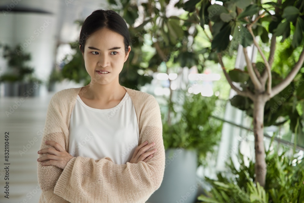 Angry upset young asian woman frowning, biting lips, expressing bad negative stressful facial expression, stress and anger management concept image Angry upset young asian woman frowning, biting lips, expressing bad negative stressful facial expression, stress and anger management concept image