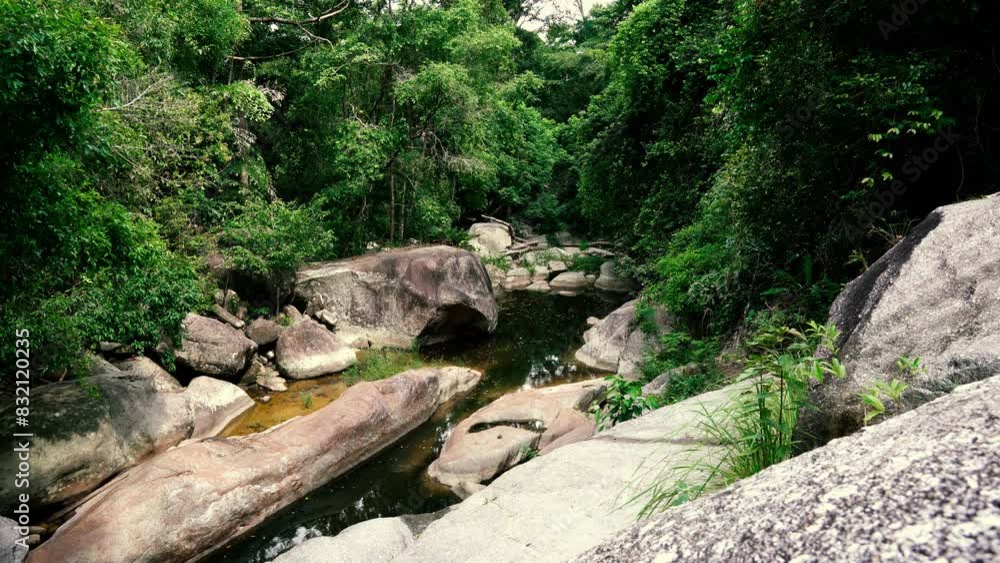 A tourist climbs rocks in the crevice of a mountain river amidst the jungle A tourist climbs rocks in the crevice of a mountain river amidst the jungle