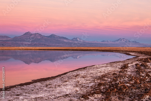 Panoramic view of mountain reflection at pink dusk in Chilen altiplano at Atacama desert with salty white soil in the foreground photo