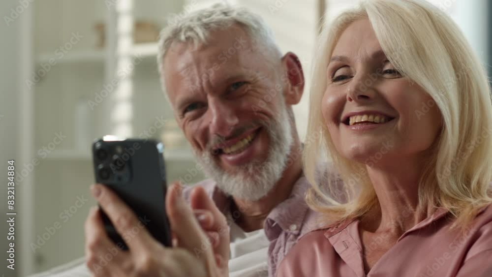 Happy Caucasian couple elderly senior mature wife husband surfing on Internet communicating social network choosing goods online man woman laugh together grandparents use mobile phone home male female Happy Caucasian couple elderly senior mature wife husband surfing on Internet communicating social network choosing goods online man woman laugh together grandparents use mobile phone home male female