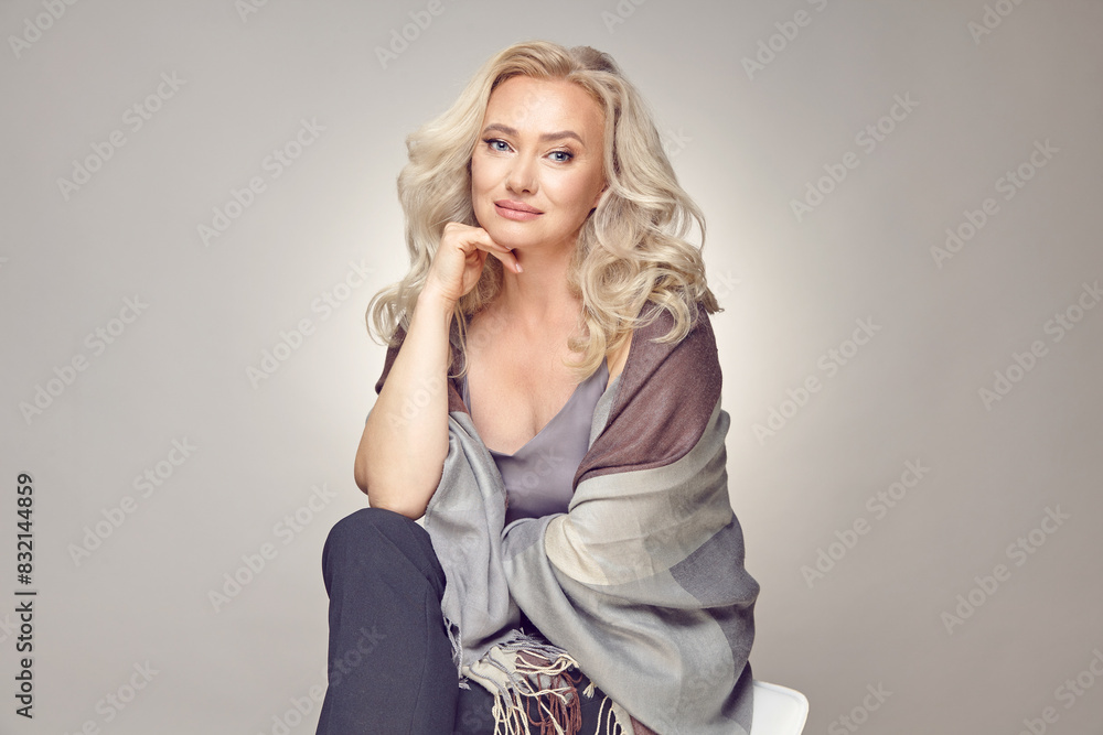 Fototapeta premium Studio portrait of luxurious fifty years old woman on a grey isolated background.