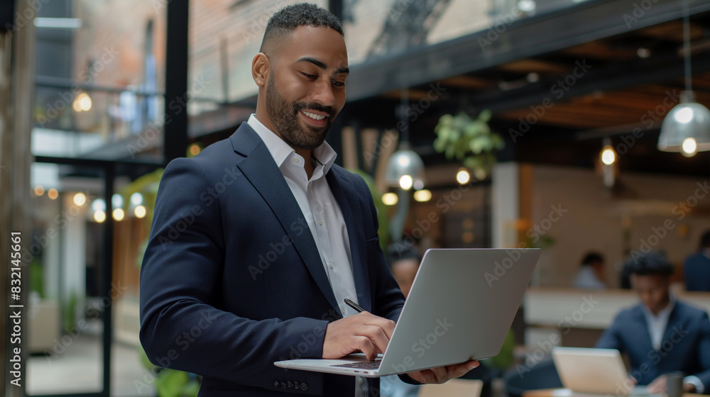 A successful brutal freelancer or CEO. A stylish guy uses a laptop, browses the Internet, looking for ideas for a project, standing in the office A successful brutal freelancer or CEO. A stylish guy uses a laptop, browses the Internet, looking for ideas for a project, standing in the office