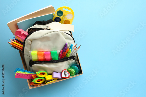 Cardboard box with backpack full of brightly colored school supplies. Back to school donation drive concept. © photoguns