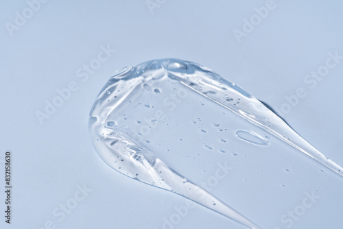 Skin care gel, face serum, swatch smear on blue background. Transparent light gelly cosmetic beauty product smudge swipe closeup