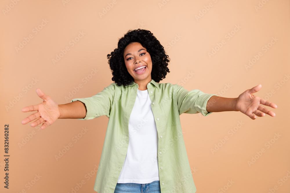 Photo of nice young lady arms welcome you wear green shirt isolated on beige color background Photo of nice young lady arms welcome you wear green shirt isolated on beige color background