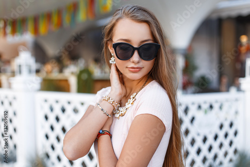 Beautiful cute fresh woman with cool sunglasses in fashion pink dress in the city