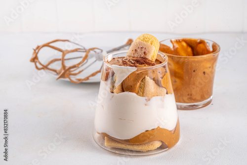 Trendy dalgona tiramisu dessert. Glass with whipped fluffy creamy coffee tiramisu, maked with instant coffee foam and savoyardi on top of it