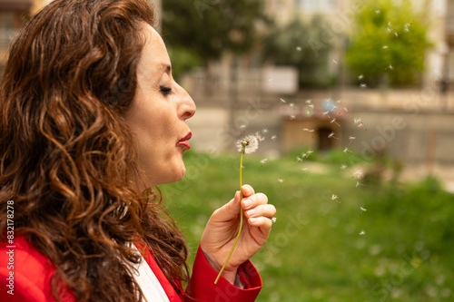 Beautiful young woman blows dandelion in a garden.