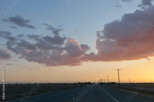 A serene highway at dusk with a vibrant sunset sky scattered with clouds. photo