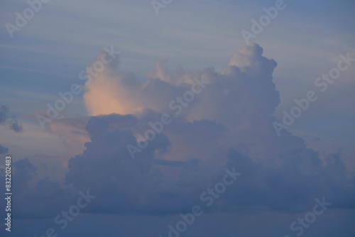 A serene sky with soft clouds tinted with pink hues from the setting or rising sun. photo