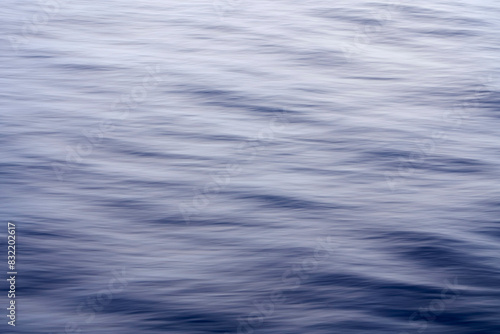 This is a tranquil image showing the smooth, flowing surface of water in shades of blue, capturing the gentle movement of the waves.